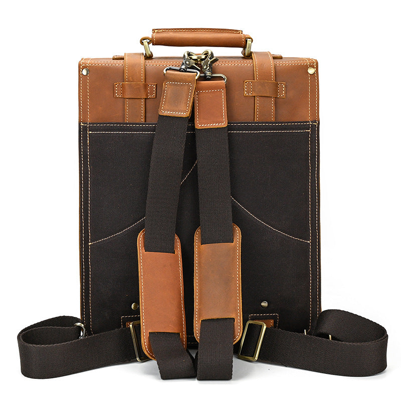 Back view of a brown and black leather briefcase with straps on a white background