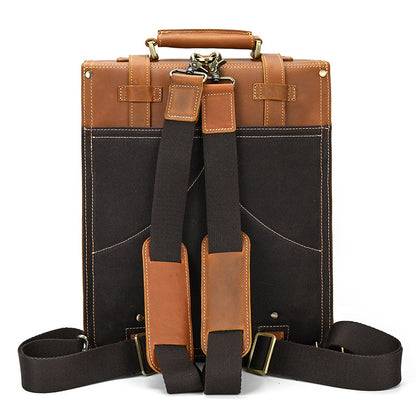 Back view of a brown and black leather briefcase with straps on a white background