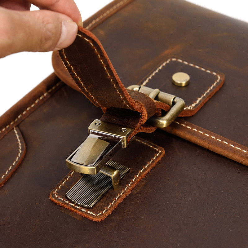 Close-up of the Brown briefcase's easy-open magnetic snap underneath the decorative buckle strap.