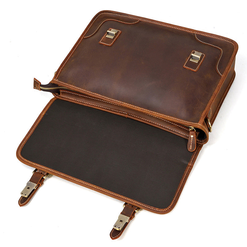 Opened Brown leather briefcase with a dark interior lining and magnetic snap closures.