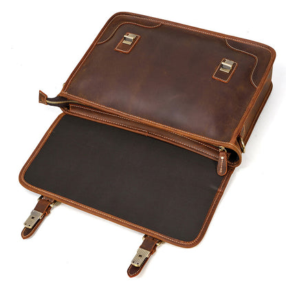 Opened Brown leather briefcase with a dark interior lining and magnetic snap closures.