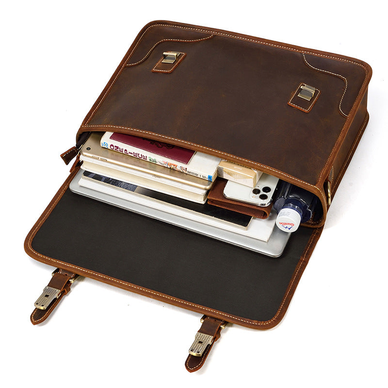 Opened Brown leather business bag packed with a laptop, notebooks, and personal items, demonstrating capacity.