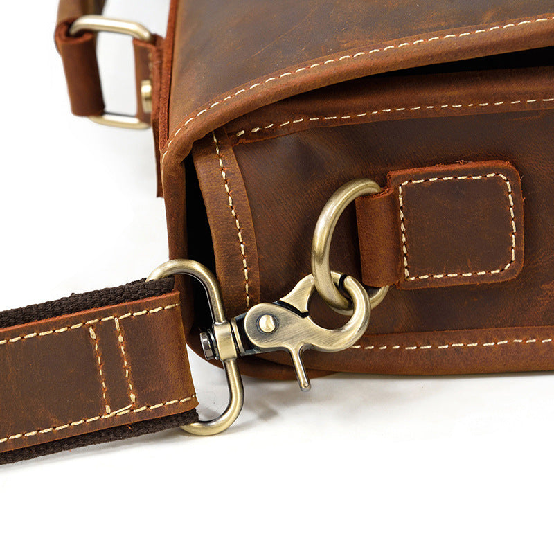 Close-up of the antique brass hardware swiveling hook and full-grain leather attachment on the Brown briefcase.