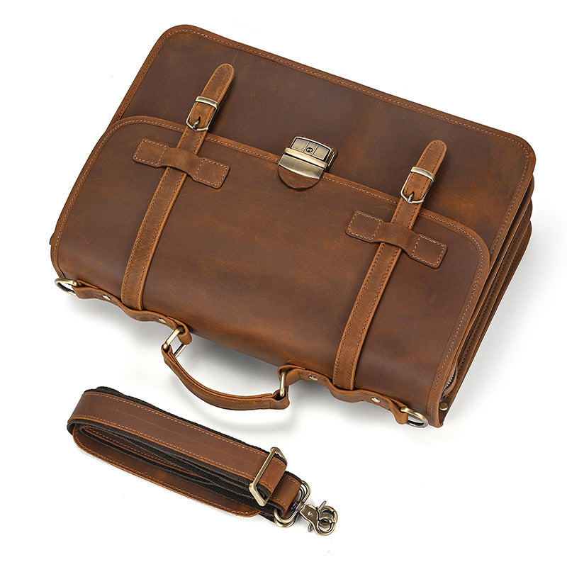 Flat lay of light brown leather briefcase and detachable shoulder strap on white background.