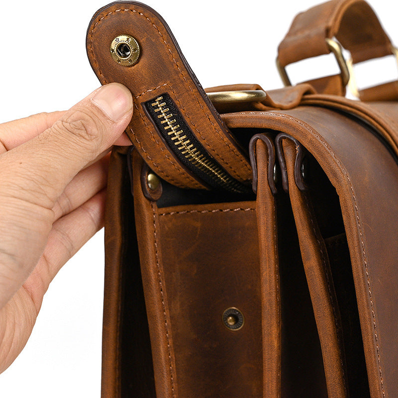 Close-up of heavy-duty brass zipper and reinforced stitching on light brown leather business bag.