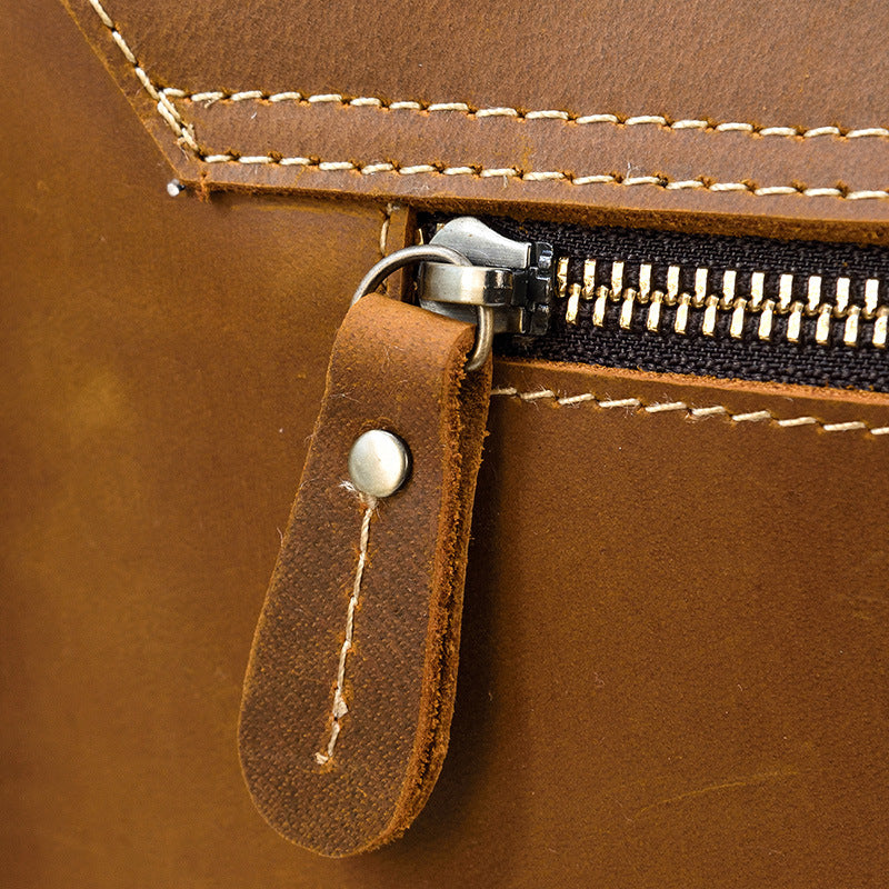 Close-up of a brown leather bag with a zipper and leather pull tab.