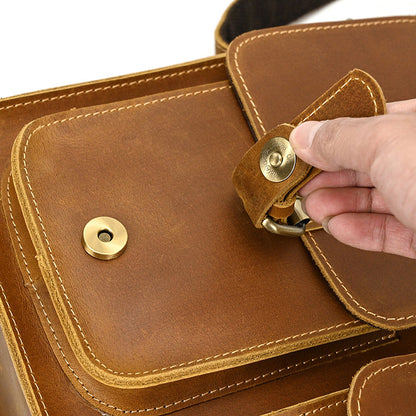 Brown leather bag with gold accents held by a hand on a white background