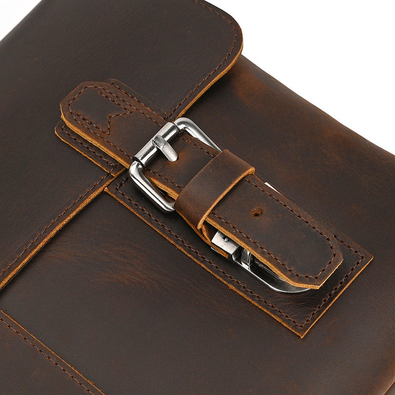 Close-up of a brown leather briefcase with a silver buckle on a white background