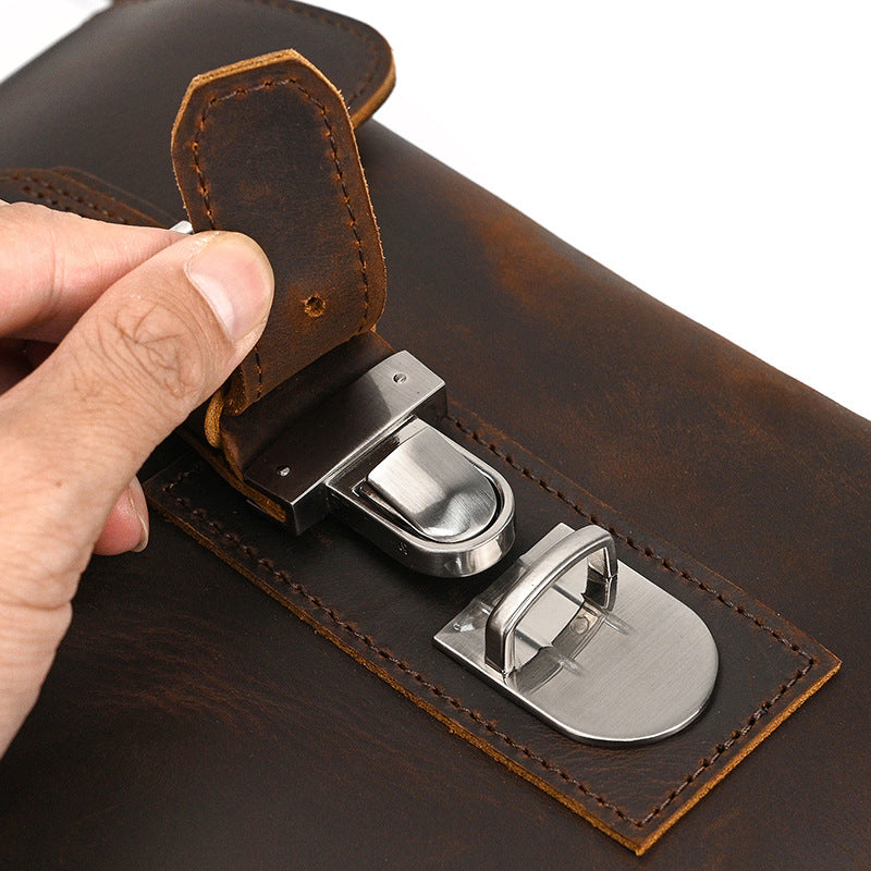 Close-up of a hand opening a brown leather briefcase with metal clasps.