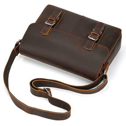 Brown leather satchel with a strap on a white background