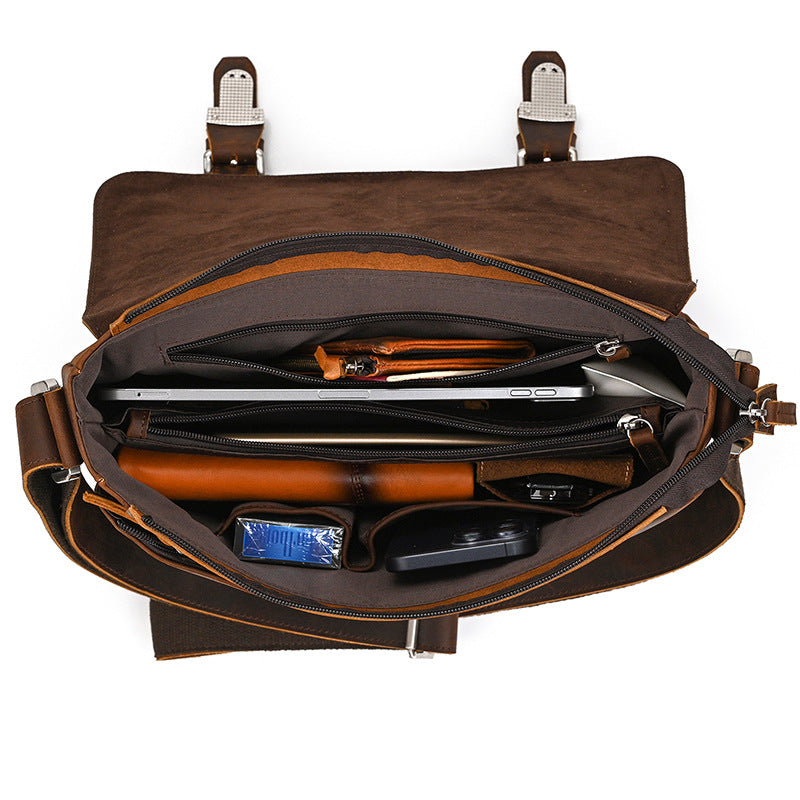 Brown leather bag with compartments containing a laptop, phone, and other items on a white background