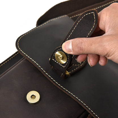 Hand holding a black leather bag with gold buttons on a white background