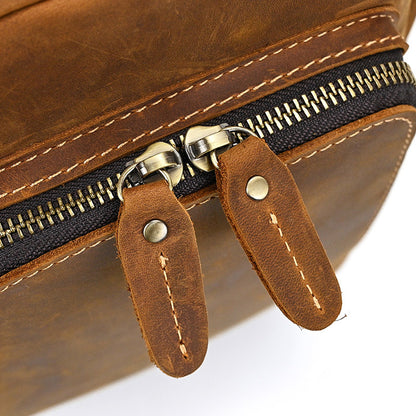 Close-up of a brown leather bag with a zipper and leather pull tabs on a white background
