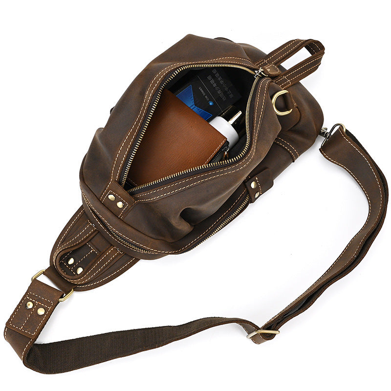 Interior of the Timber Carry Crazy Horse Leather Sling Bag packed with a wallet, lighter, and bottle, demonstrating its capacity.