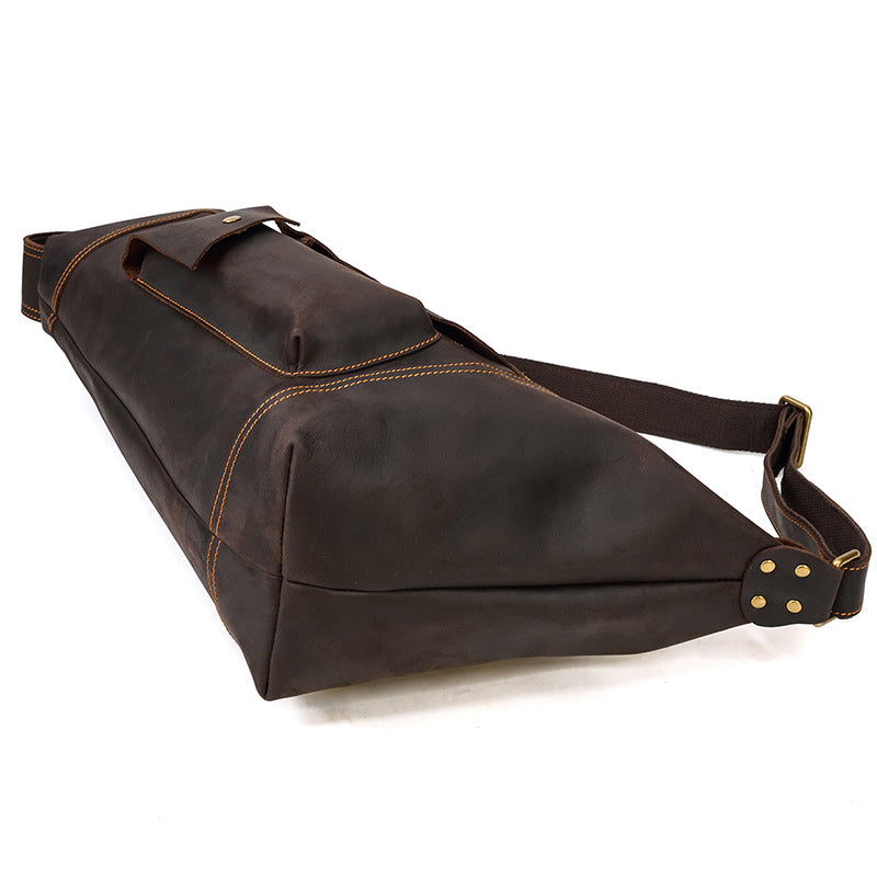 botton view of dark Brown leather bag with a strap on a white background