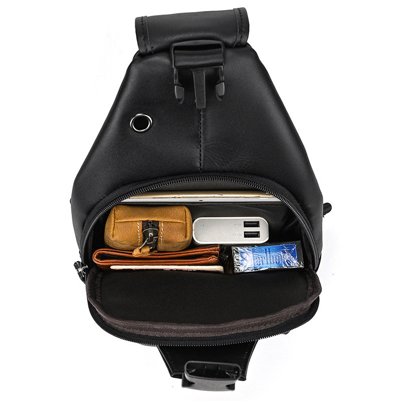 Black sling bag with compartments containing a wallet, phone, and other items on a white background