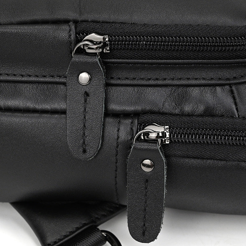 Close-up of a black leather bag with zippers and straps on a white background
