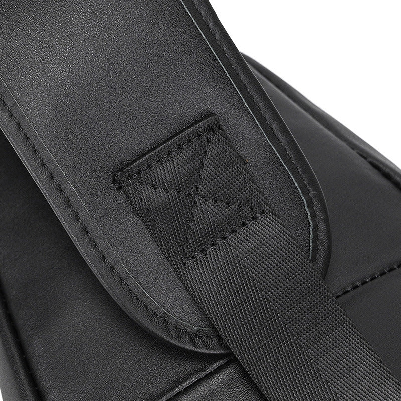 Close-up of a black leather bag with a strap and visible stitching detail.