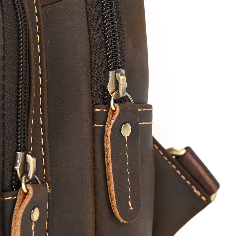 Close-up of a brown leather bag with zippers and stitching details.