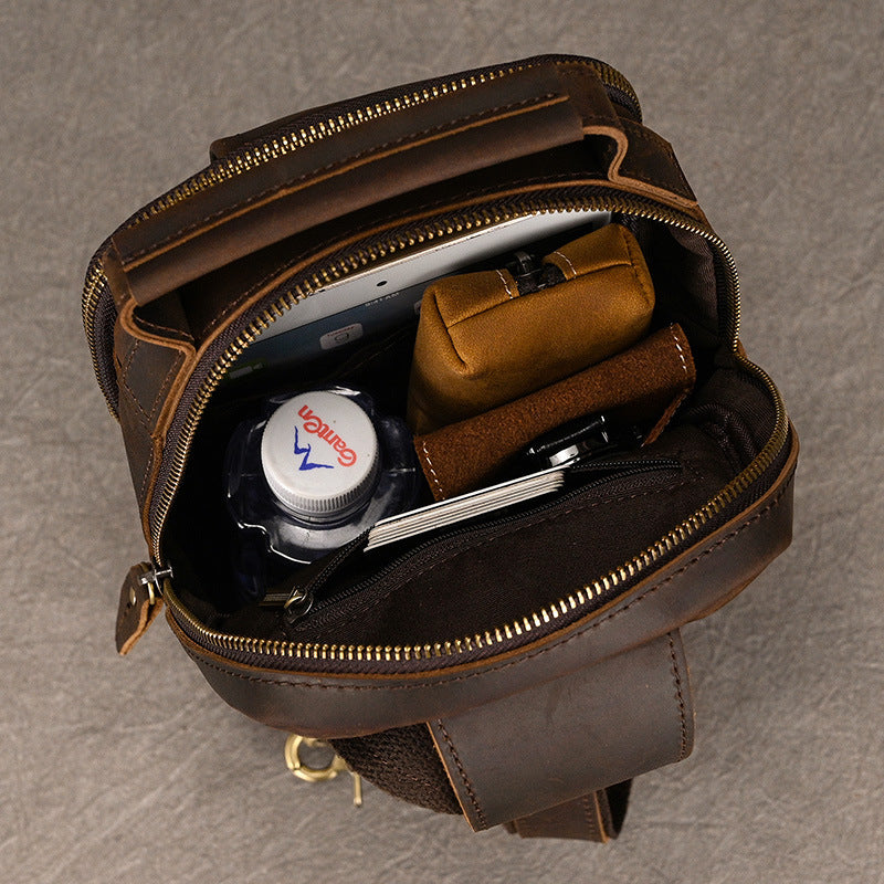 Open brown leather bag with toiletries on a gray background