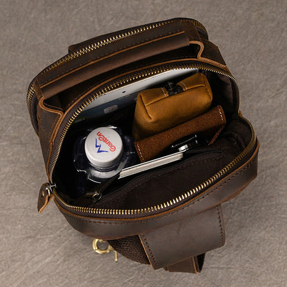 Open brown leather bag with toiletries on a gray background