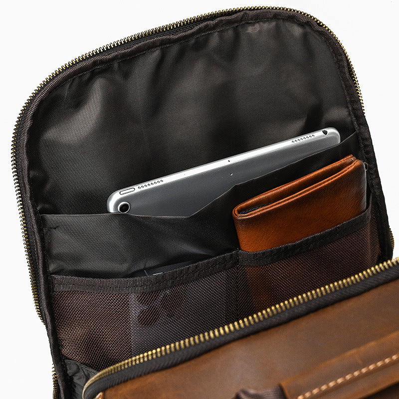 Brown leather bag with compartments holding a silver laptop and brown wallet.
