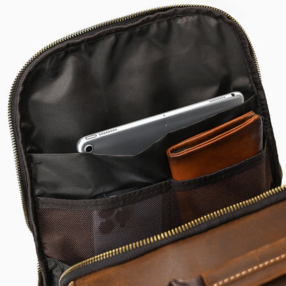 Brown leather bag with compartments holding a silver laptop and brown wallet.