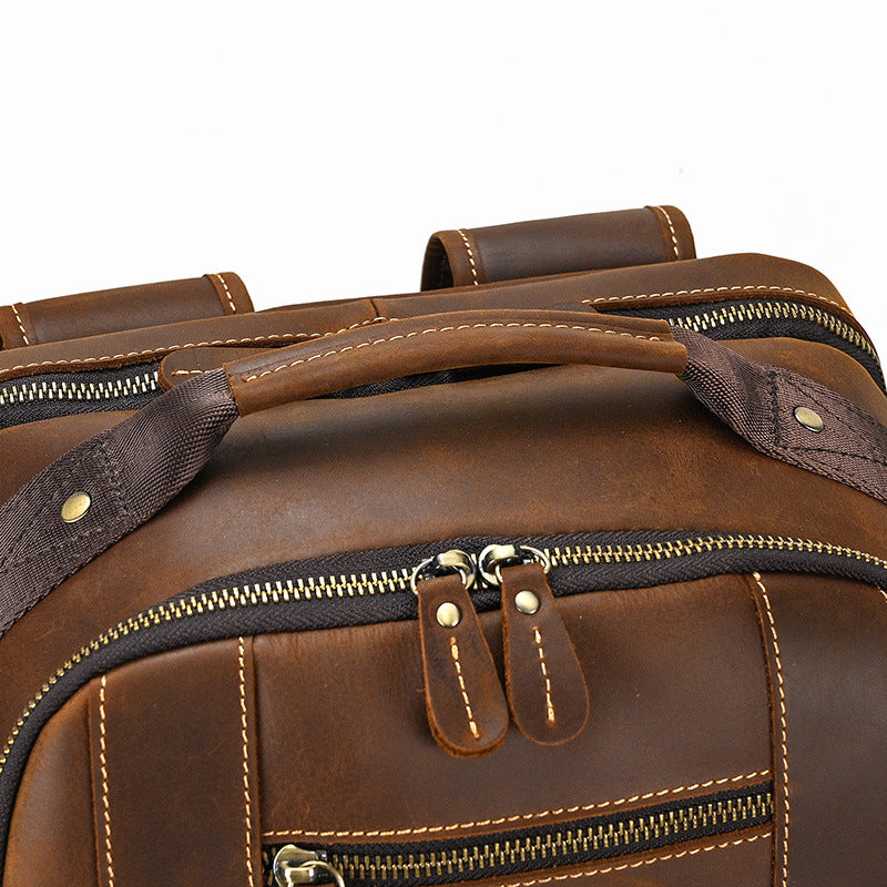 Close-up of a brown leather bag with zippers and handles on a white background