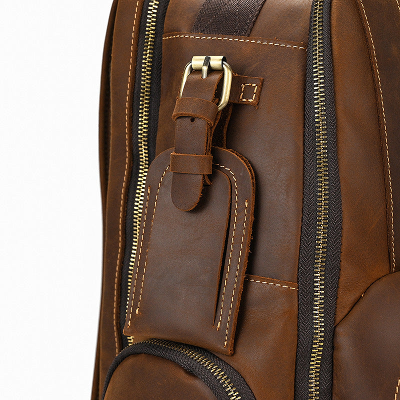 Close-up of a brown leather backpack with gold zipper and buckle details.