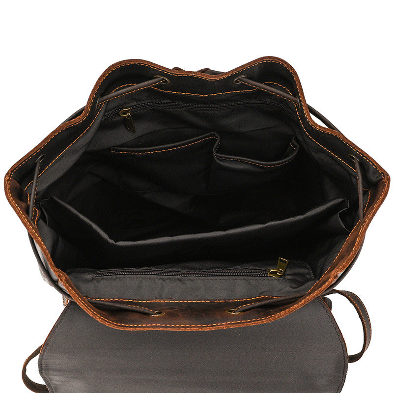 Open brown leather backpack with black interior on a white background