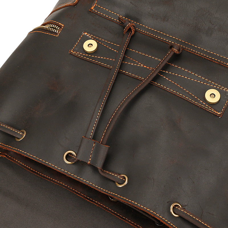 Close-up of a dark brown leather bag with gold stitching and buttons.
