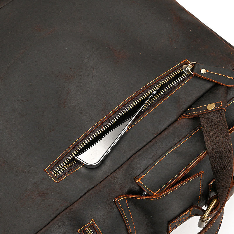 Close-up of a brown leather bag with a zipper and stitching details.