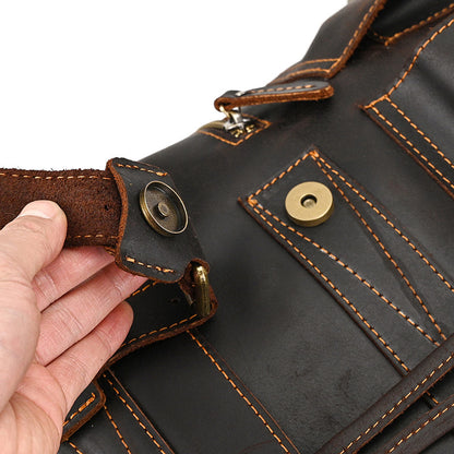 Close-up of a brown leather bag with stitching and buttons, held by a hand.