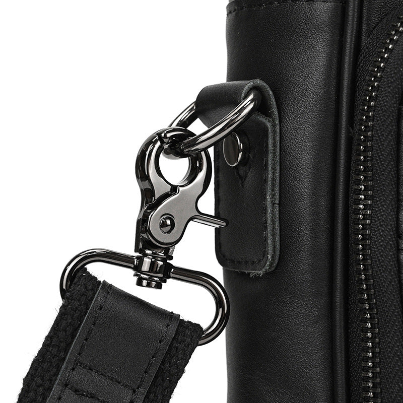 Close-up of a black leather bag with a metal clasp and strap on a white background