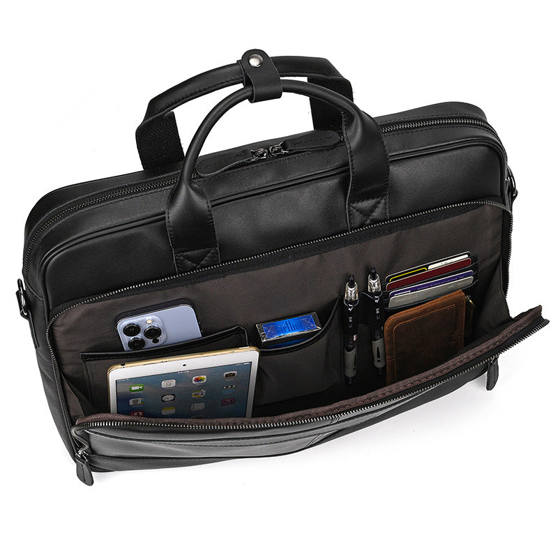 Black briefcase with multiple compartments and electronic devices inside on a white background