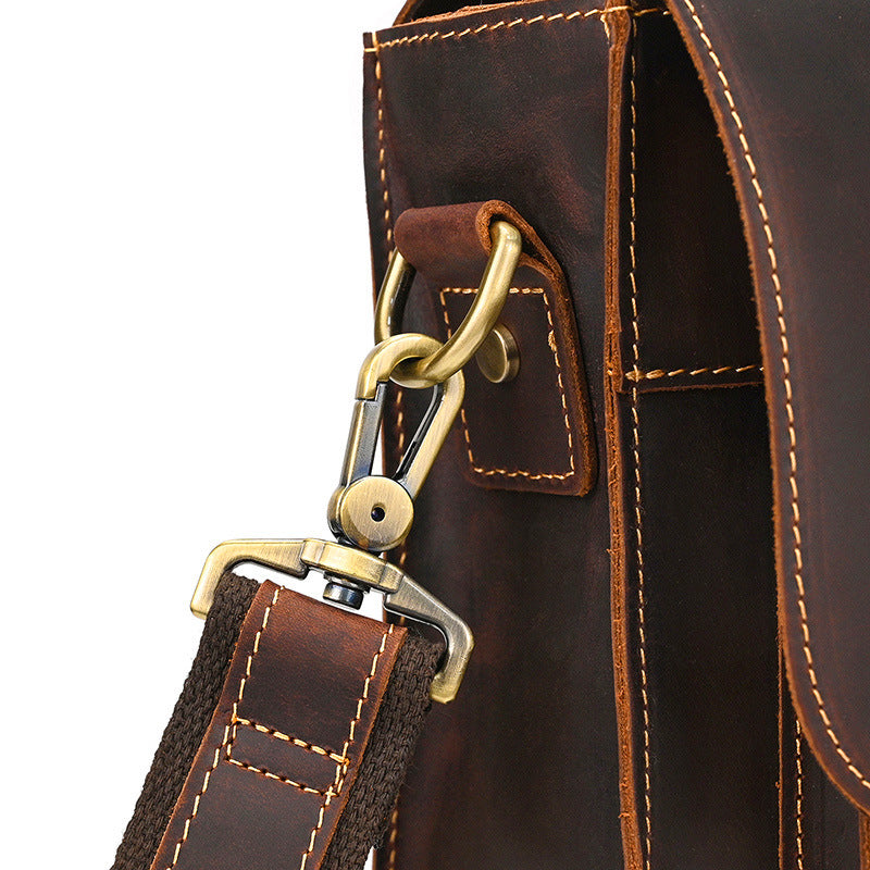 Close-up of durable rolled leather handle with strong brass D-rings for shoulder strap attachment.