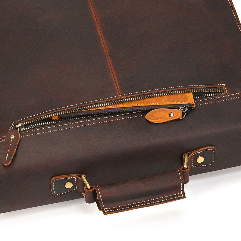 Brown leather briefcase with gold zipper and hardware on a white background