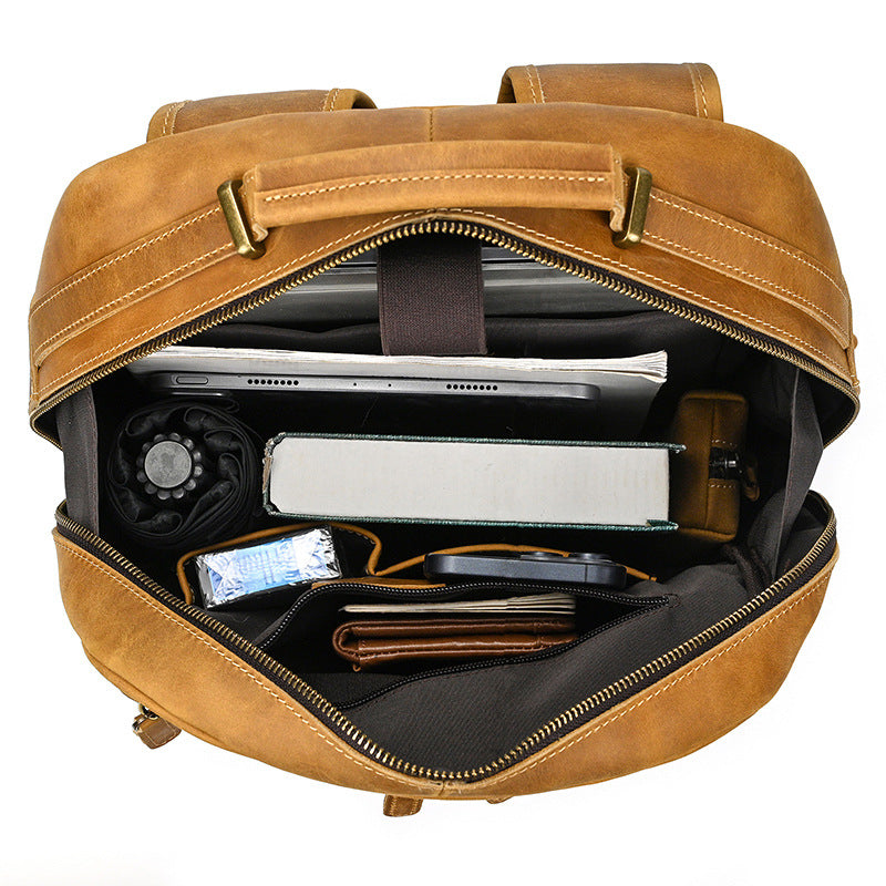 Brown leather backpack with compartments and items inside on a white background