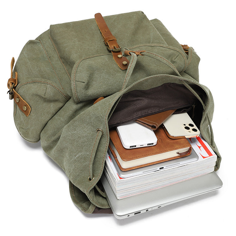 Interior view of the Timbercarry vintage canvas multi-pocket backpack filled with items including a laptop, tablet, notebook, and smartphone, demonstrating its spacious storage capacity.
