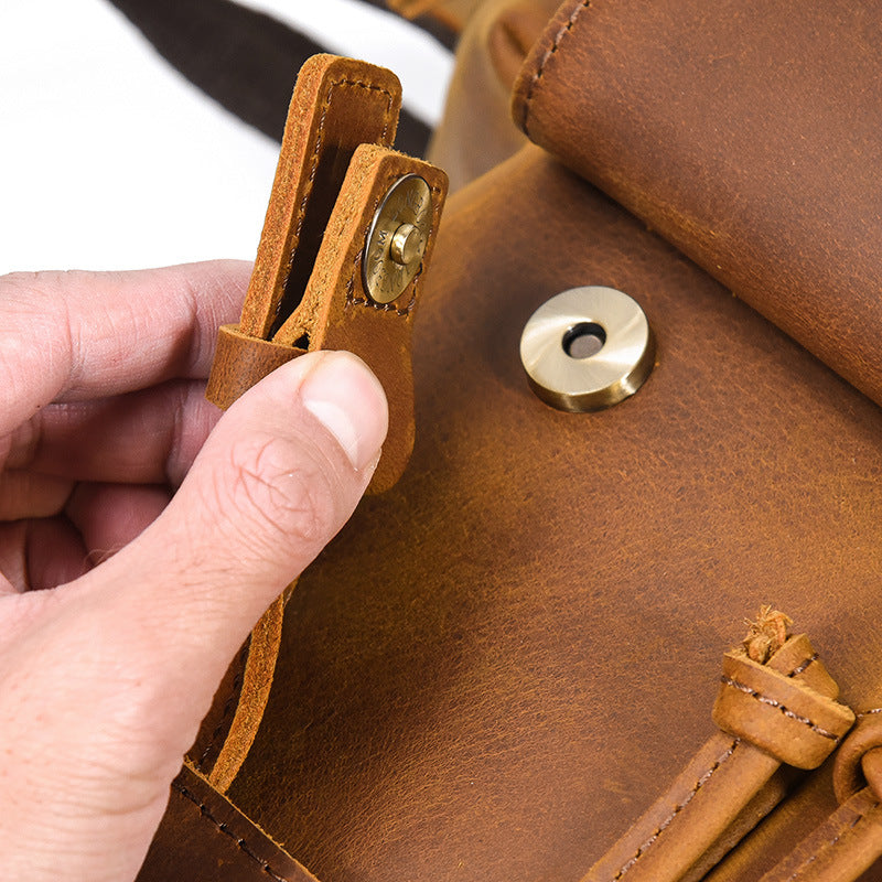 Close-up of a hand adjusting a brown leather strap on a bag.
