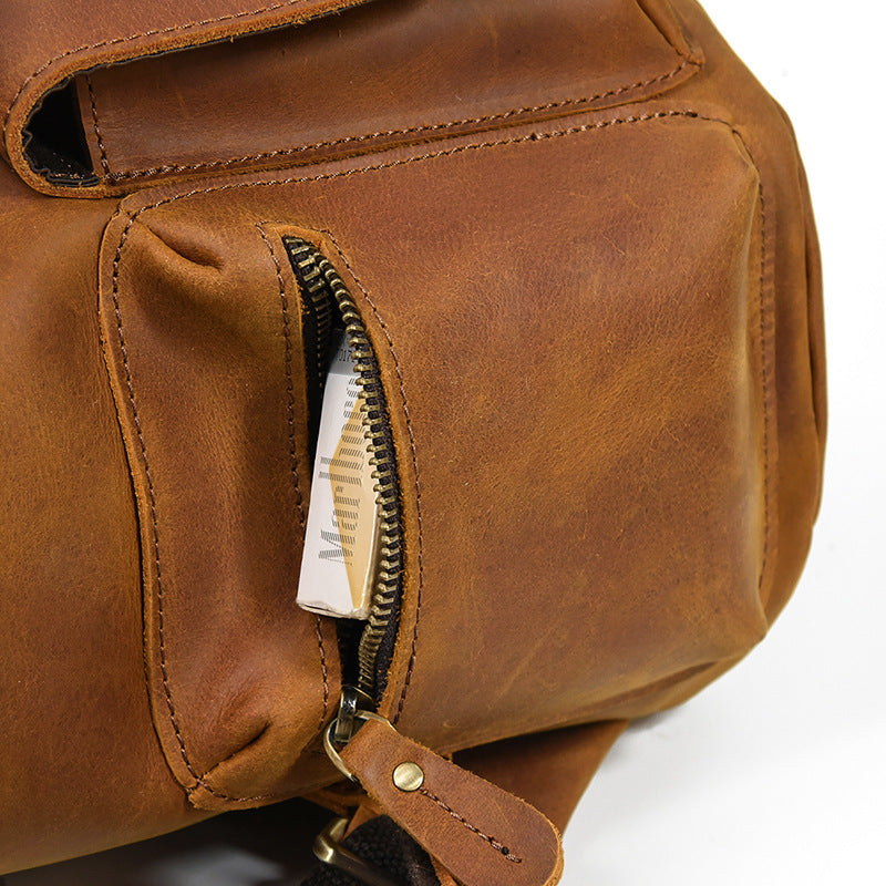 Close-up of a brown leather bag with a zipper pocket on a white background