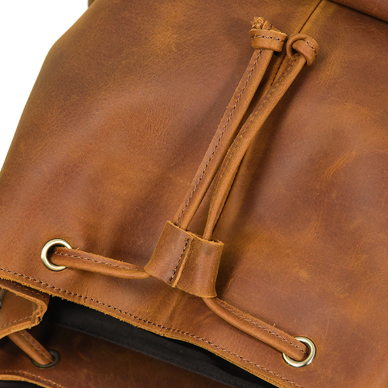 Close-up of a brown leather bag with drawstring and metal eyelets.