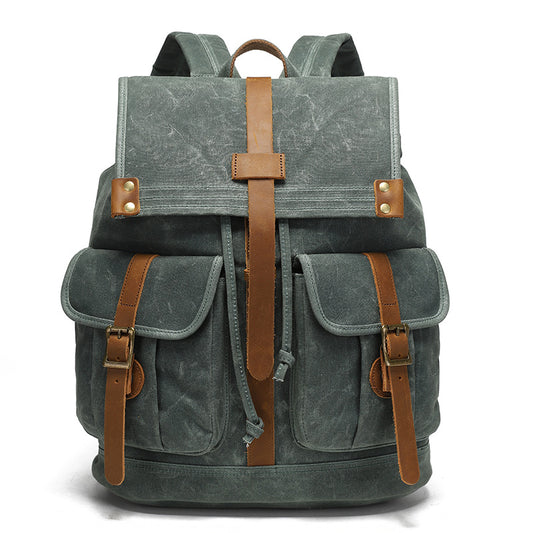 Vintage Waxed Canvas Rucksack Backpack - Front view of the forest green version, featuring durable waxed canvas, two front pockets with brown leather straps, and brass hardware.