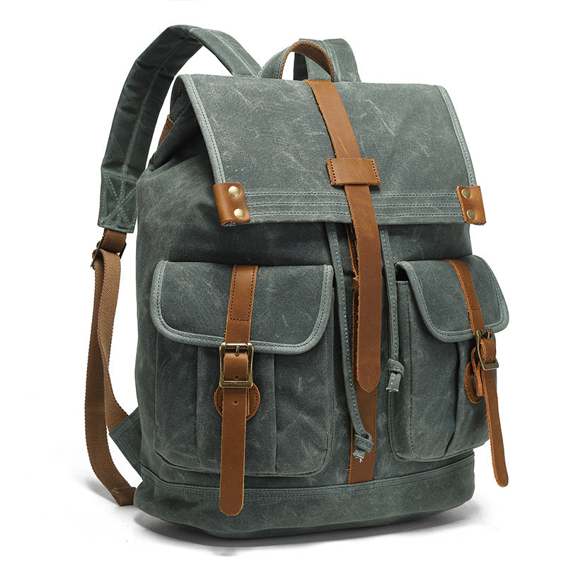 Vintage Waxed Canvas Rucksack Backpack - Angled view of the forest green version, showcasing the side profile, padded shoulder straps, and leather-accented front pocket flap.