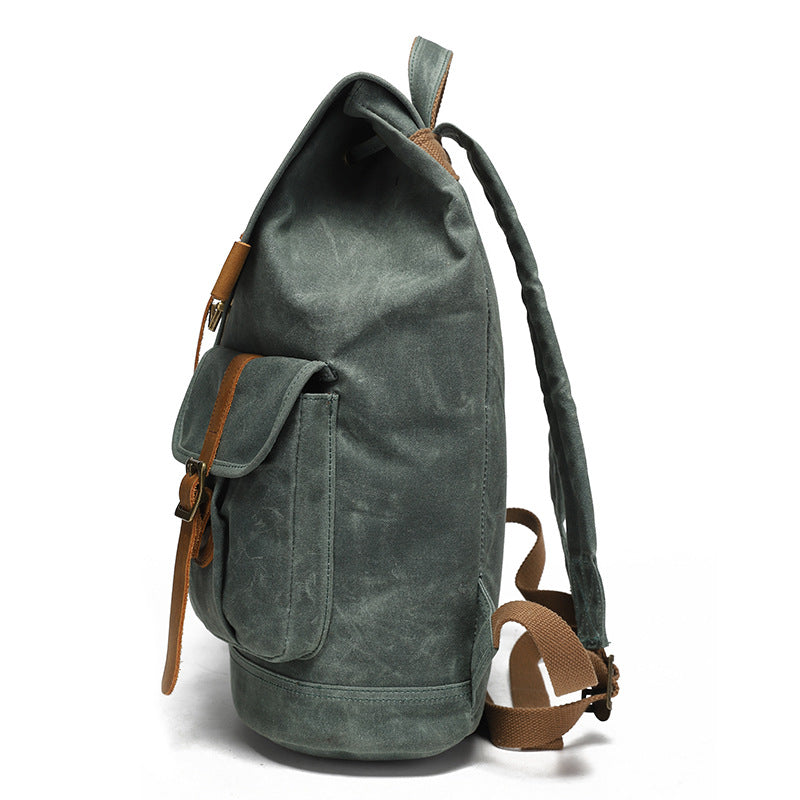 Vintage Waxed Canvas Rucksack Backpack - Side view of the forest green version, highlighting the spacious side pocket, rugged waxed canvas texture, and adjustable brown shoulder strap.