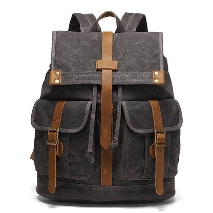 Vintage Waxed Canvas Rucksack Backpack - Front view of the dark charcoal gray version, with signature waxed canvas material, brown leather straps, and brass buckle details.