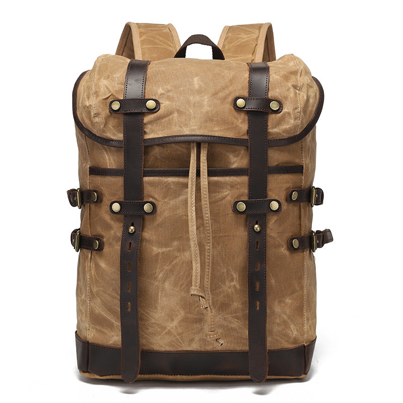 Vintage waxed canvas rucksack in brown with dark leather buckle straps and brass hardware, front view.