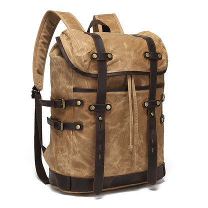 Side-angle view of the vintage waxed canvas backpack showing adjustable leather buckle strap details and side compression straps.