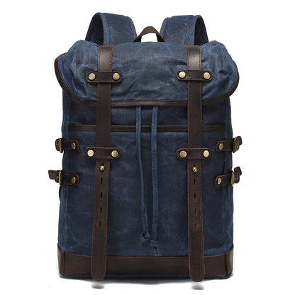 Vintage waxed canvas rucksack in navy blue with premium leather buckle straps and antique brass detailing.