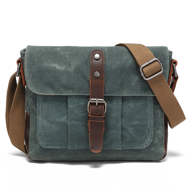 Vintage blue-grey waxed canvas messenger bag with premium leather accents, front view.
